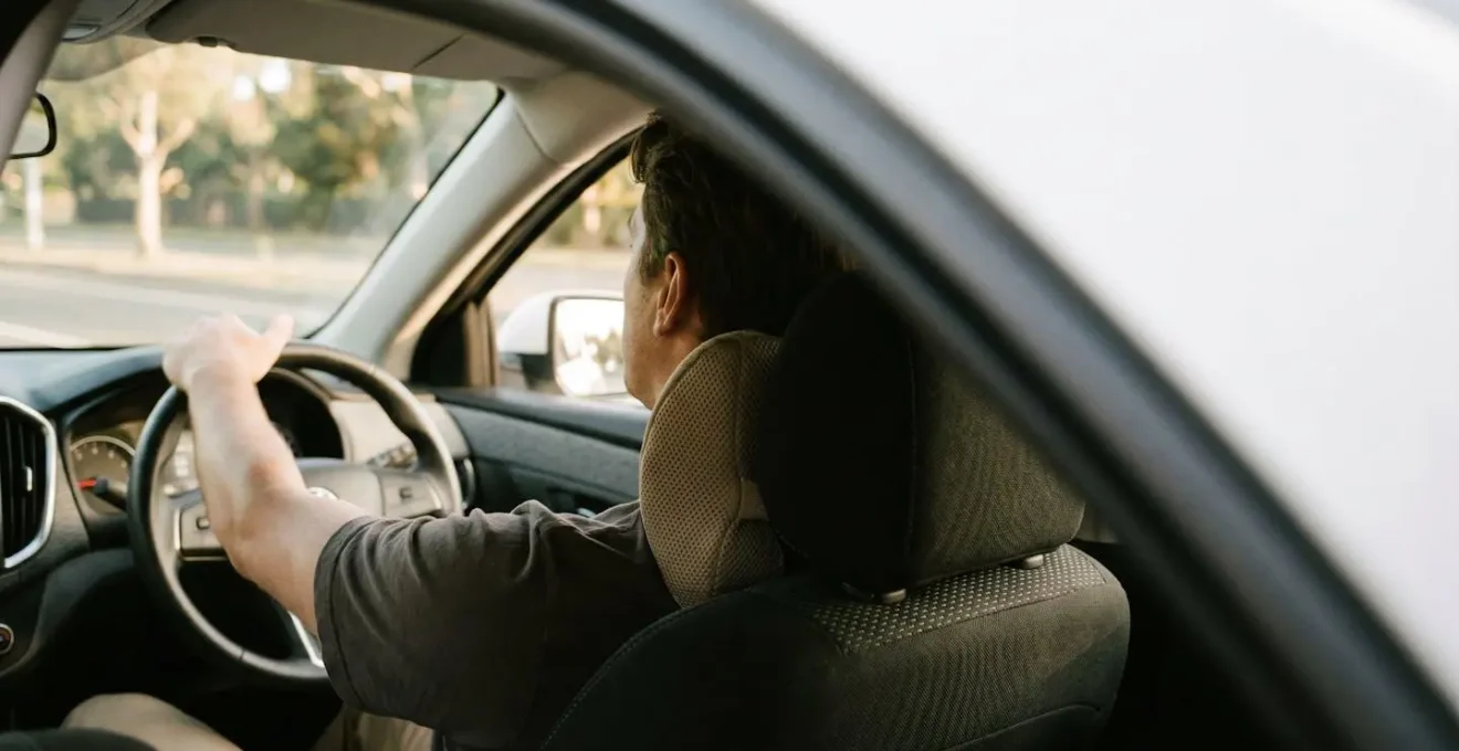 Conducteur de profil avec un coussin lombaire ergonomique installé contre le bas du dos sur un siège de voiture