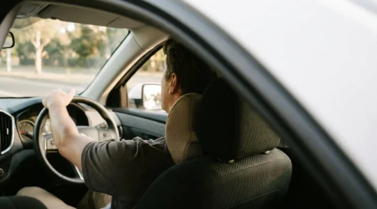Conducteur de profil avec un coussin lombaire ergonomique installé contre le bas du dos sur un siège de voiture