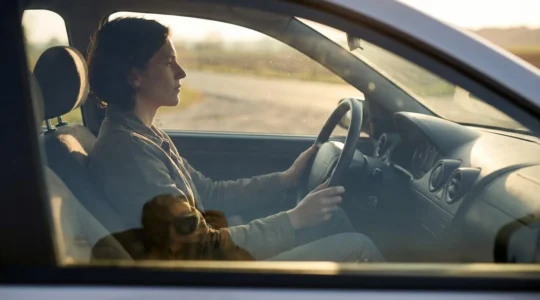 Conducteur assis avec une posture alignée, dos droit et mains détendues sur le volant, illustrant l'équilibre de la colonne vertébrale au volant